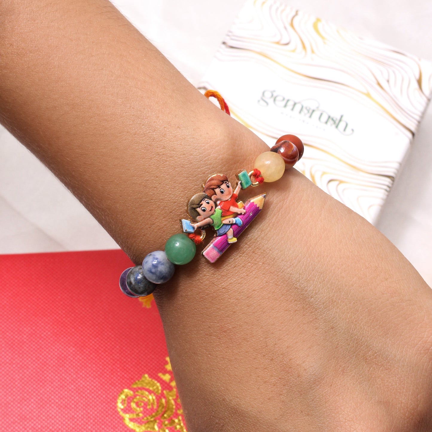 Cartoon School-Themed Gemstone Rakhi for Kids – Colorful Beads with Pencil Ride Charm